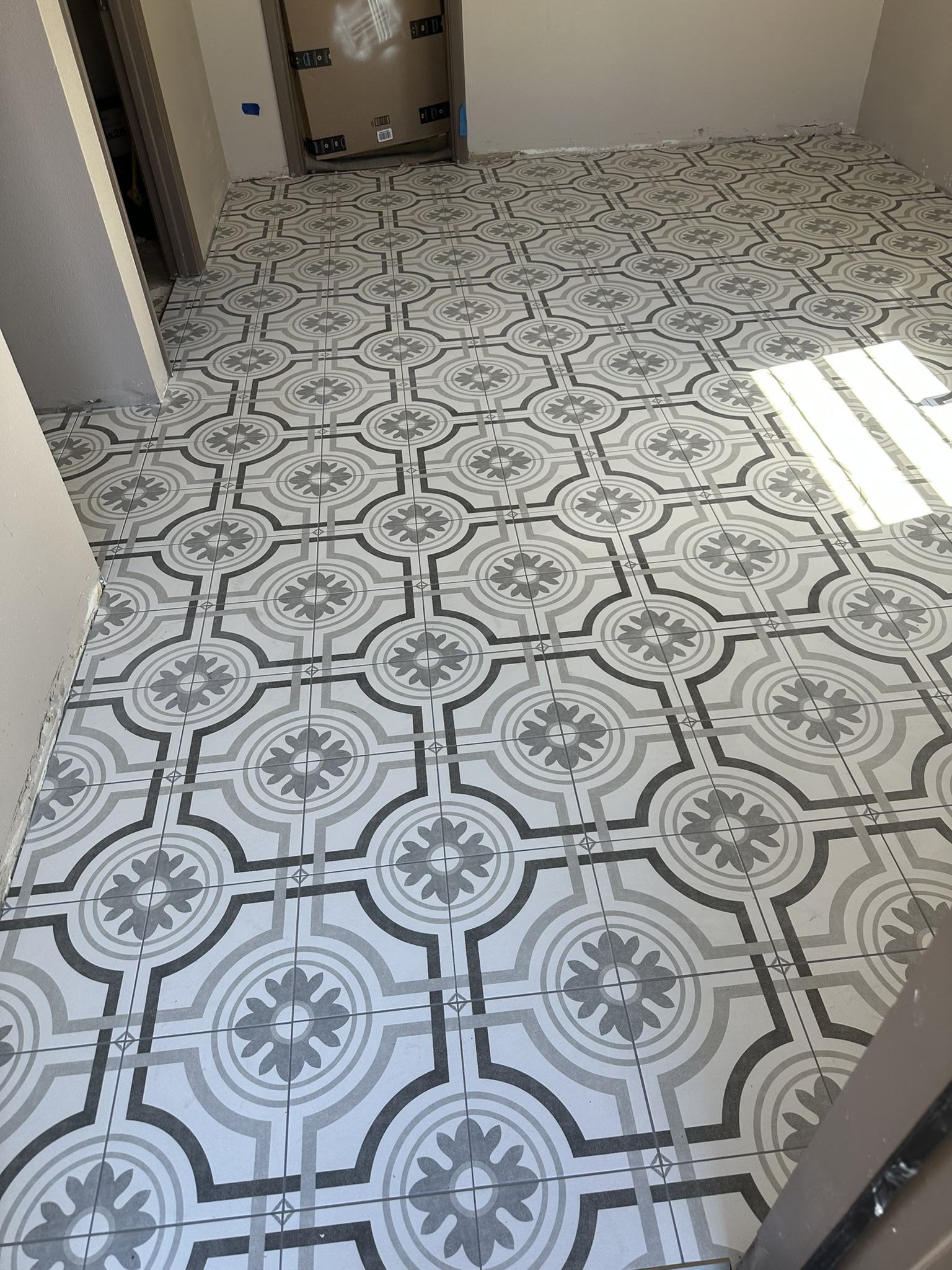 Gray and white floral-patterned tile floor during installation