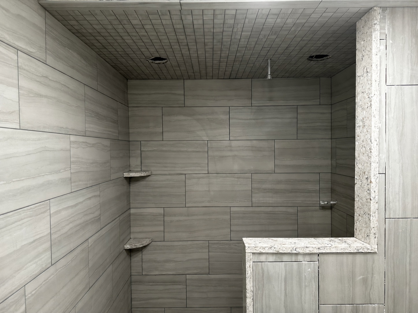 Aligned stone-look tile across shower walls and ceiling during installation